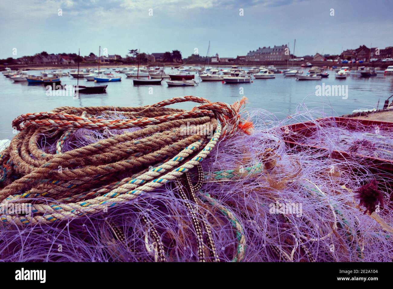 Normandy, France. Colorful fishing net drying on pier after fishermen back  with fresh catch; mooring boats and Saint-Vaast-la-Hougue houses at backgro  Stock Photo - Alamy