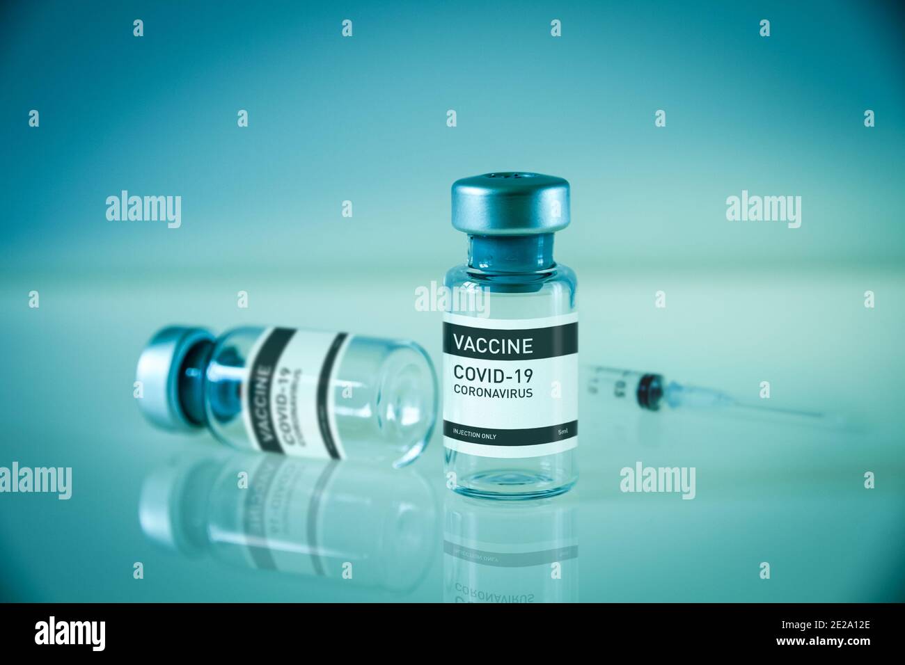 Covid-19 vaccine bottle and syringe on a blue laboratory background ...