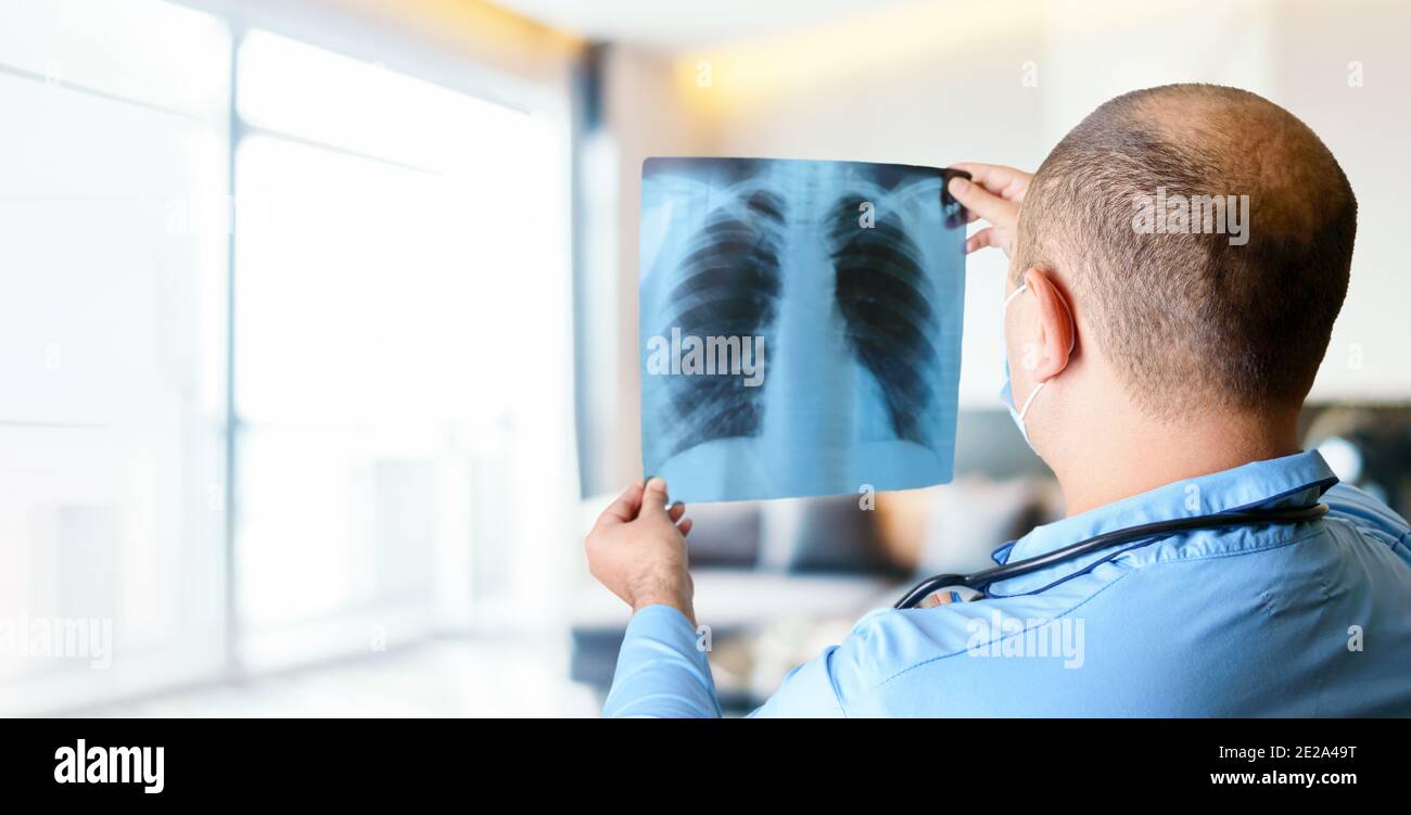 A doctor reads a chest xray in the bright hospital's waiting room. The