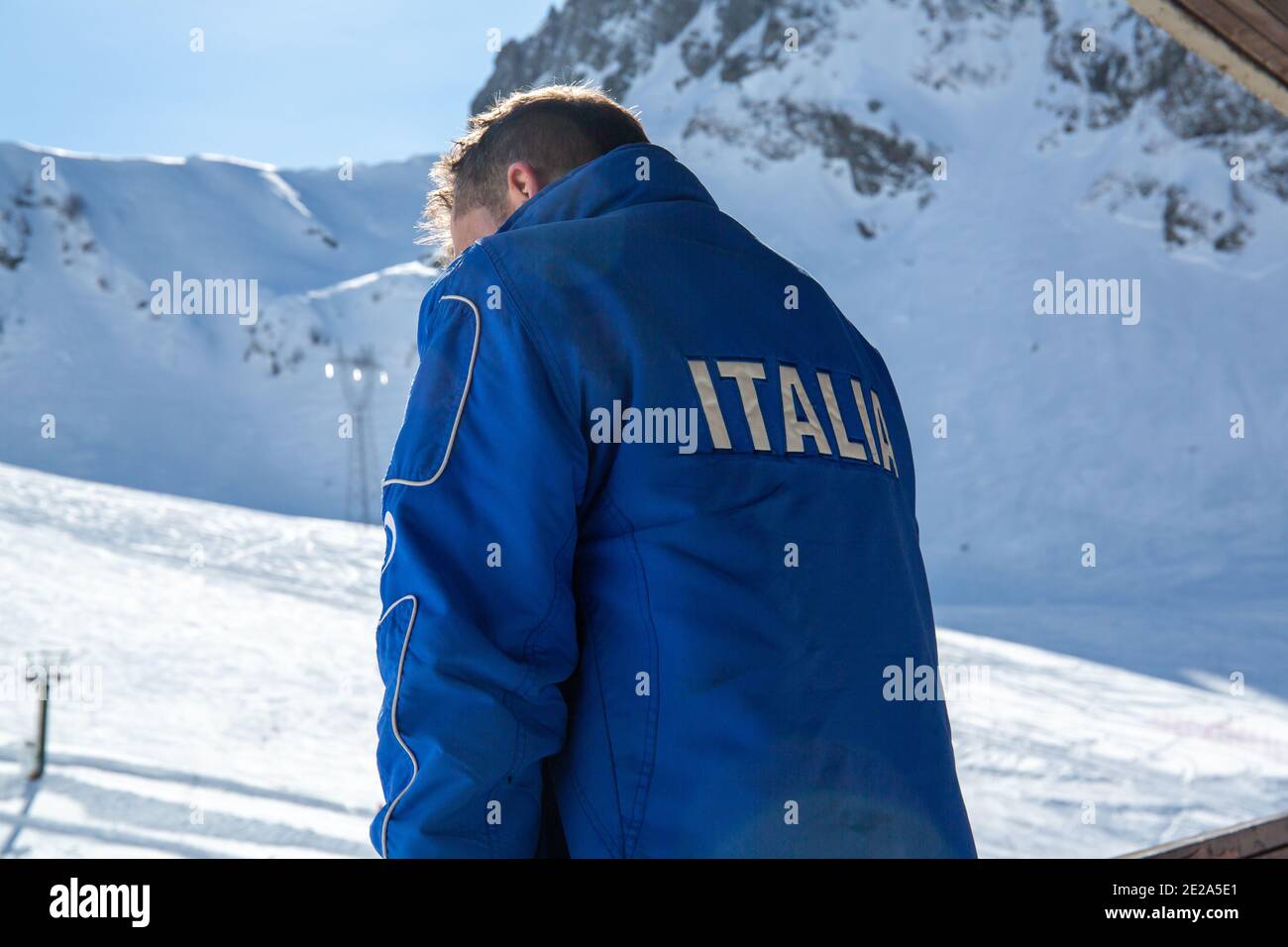 Italian Alps and an Italian ski instructor. Ski slopes are closed and empty due to the Coronavirus pandemic.Mountain tourism business crisis. Stock Photo