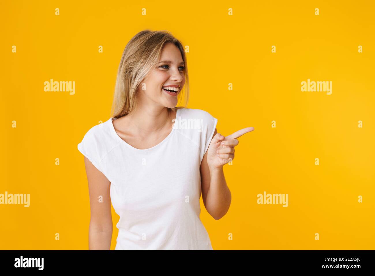Cheerful beautiful girl smiling while pointing finger aside isolated ...