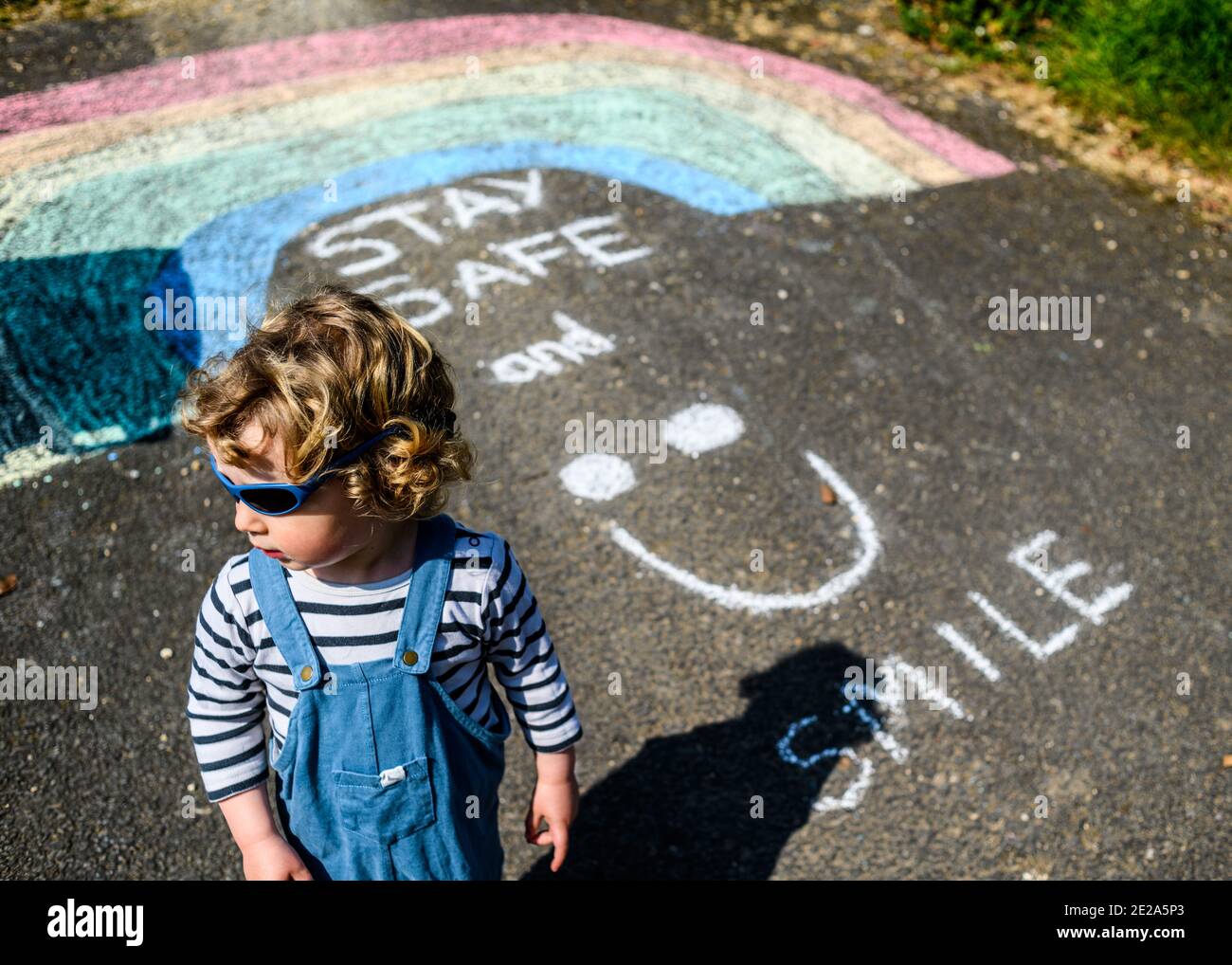 A child walks past a rainbow street chalk drawing during lockdown in the UK Stock Photo