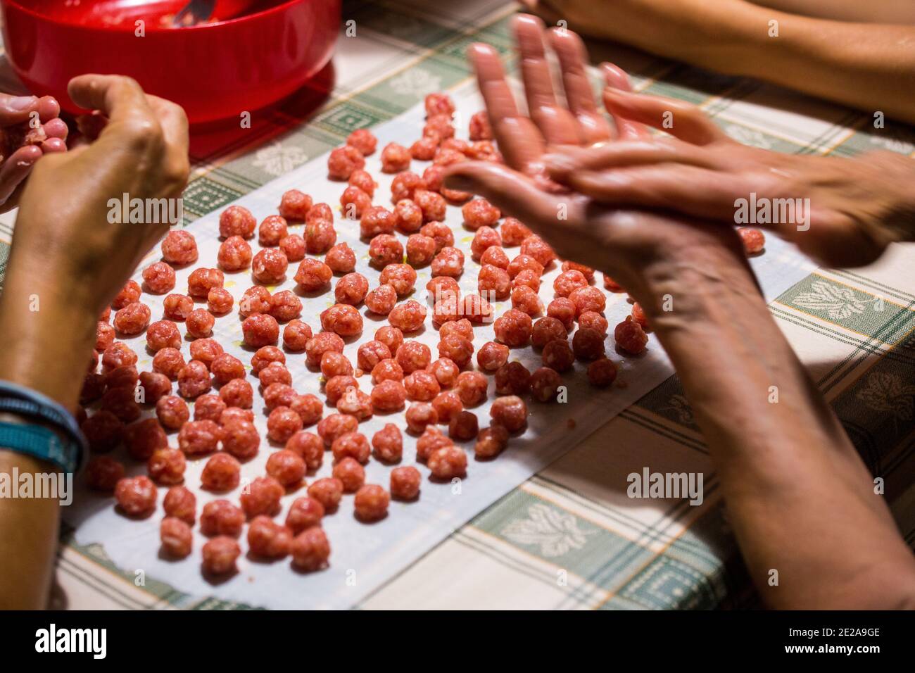 Two people prepare raw meatballs, roll them up with their hands and are ready to be cooked. Meatballs. meat ball, meat ball. Stock Photo
