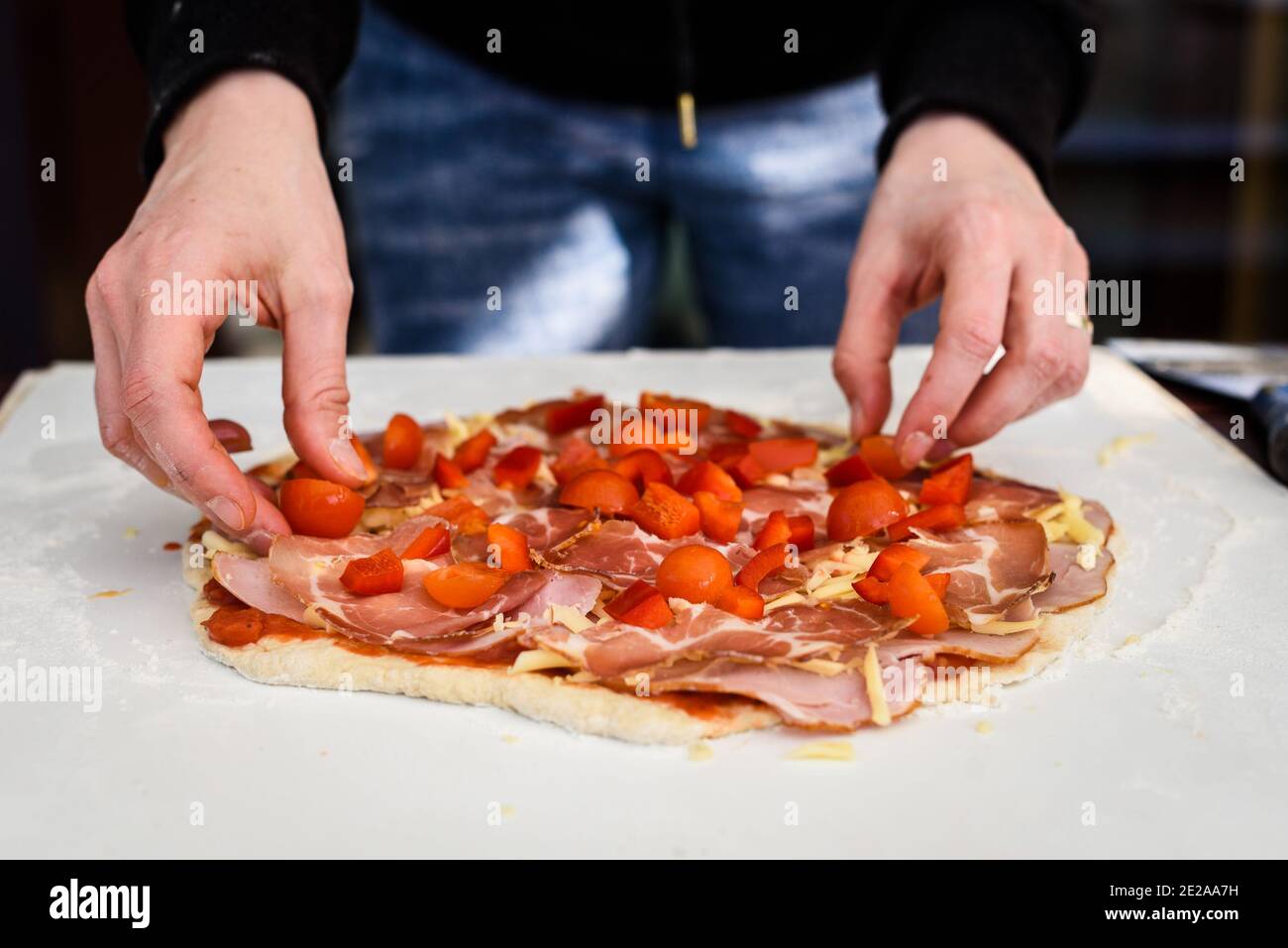 Making of homemade Italian pizza in fireplace brick oven. Making of pizza and adding different ingredients before baking it in outside fireplace. Hand Stock Photo