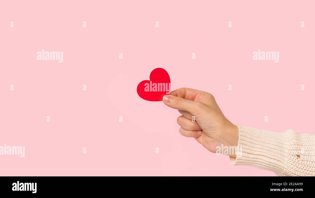 Woman hands holding red heart on pink background Stock Photo - Alamy