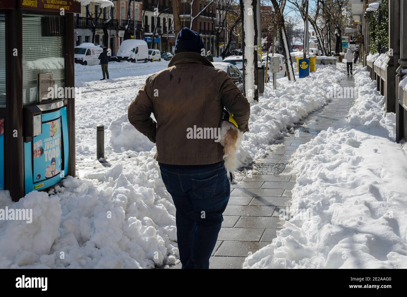 Madrid, Spain. 10 th January 2021. View of a man with dog in San Bernardo street, Chamberi quarter, after the snow storm. Credit: Enrique Davó. Stock Photo