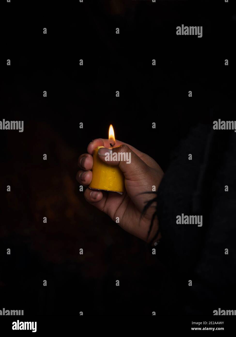 Woman holding yellow burning wax candle in her hands memorial grief