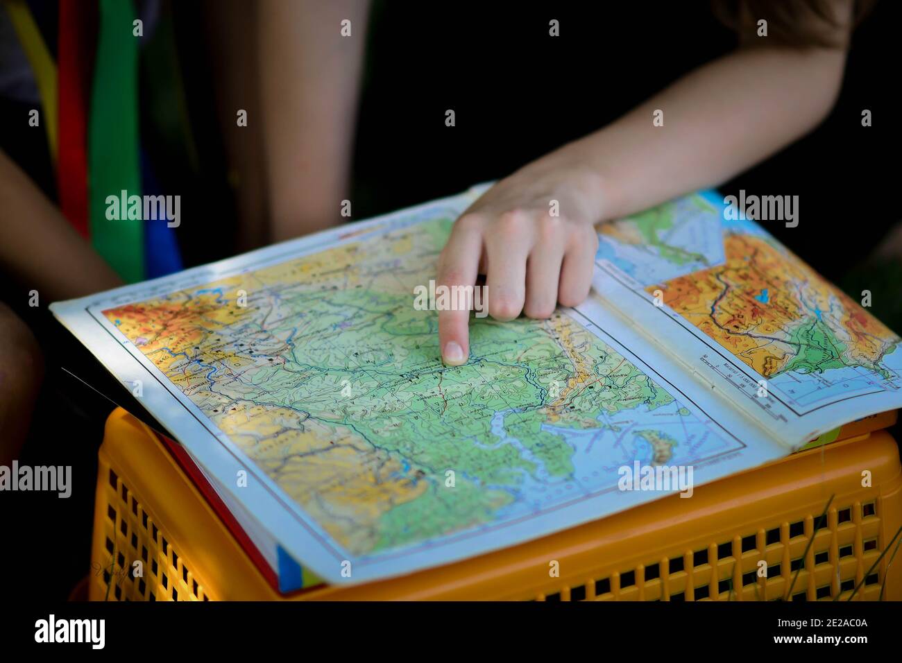 the girl is looking at a geographical atlas. geographical map in the hands of a schoolboy girl. Stock Photo