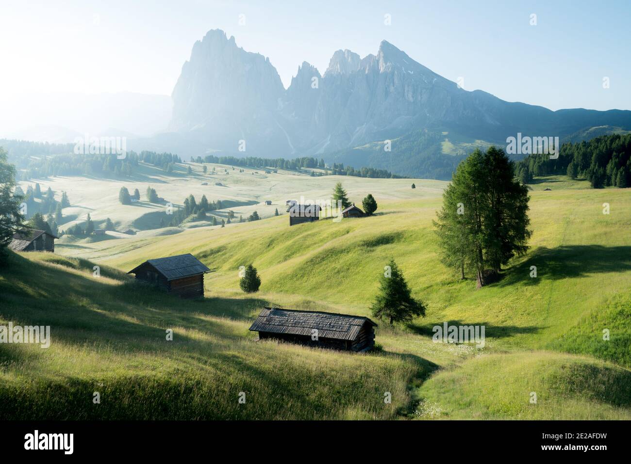 Idyllic mountain scenery in the Dolomites with traditional mountain cabins during a peaceful sunrise in spring, Alpe di Siusi, South Tyrol, Italy Stock Photo