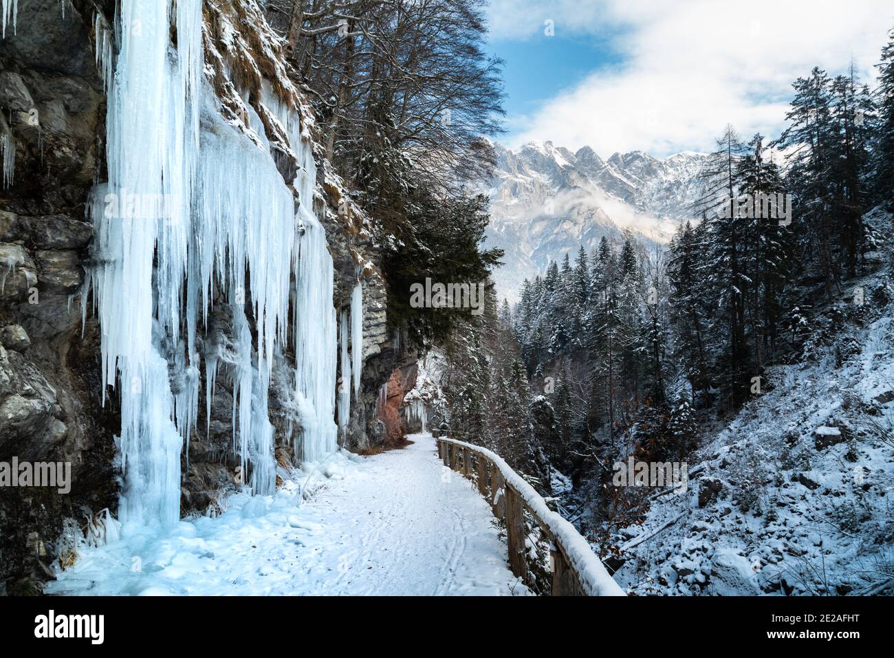 Beautiful panorama view of idyllic winter wonderland scenery with icicles and trail alongside a steep canyon in the Alps on a cold sunny winter day Stock Photo