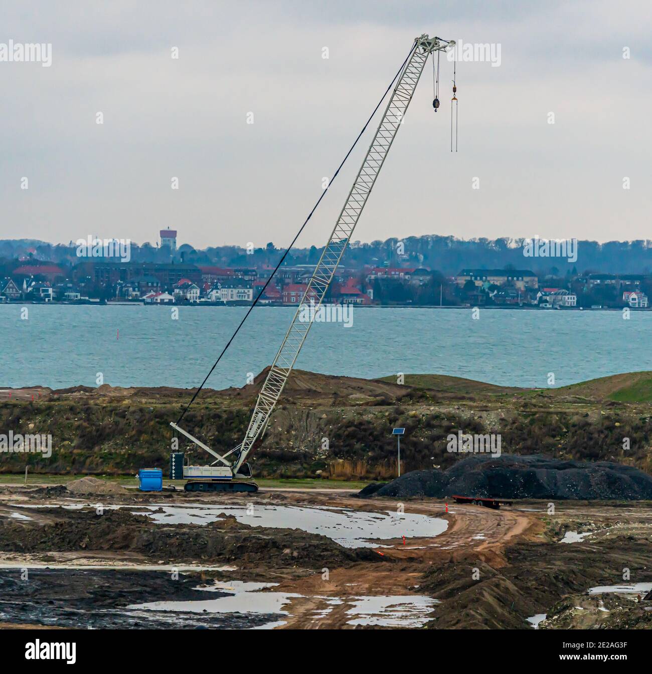 Large industrial construction crane at a work site near the sea. Stock Photo
