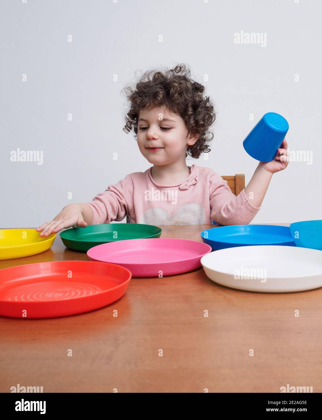a-toddler-plays-with-plastic-dishes-at-a-table-stock-photo-alamy