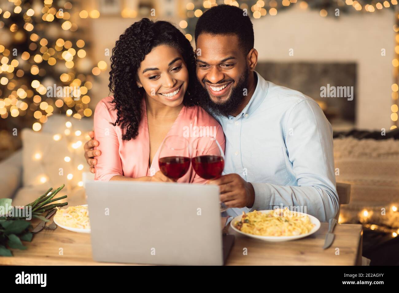 Black couple having videocall using laptop drinking wine Stock Photo