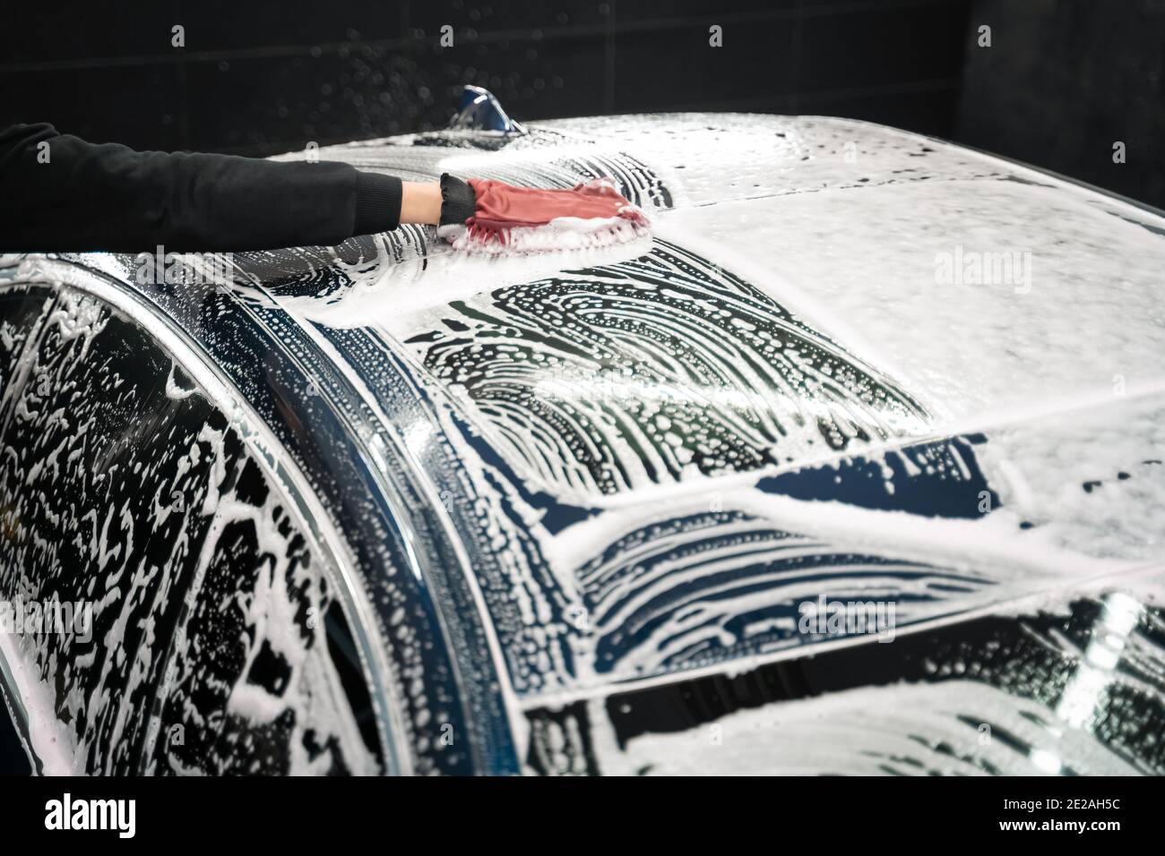 Professional car wash. Detailing worker washes the vehicle body with