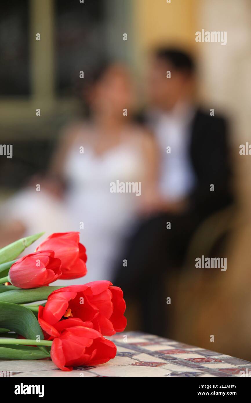 Wedding Concept Bridal flower bouquet with an out of focus bride and groom in the background Stock Photo
