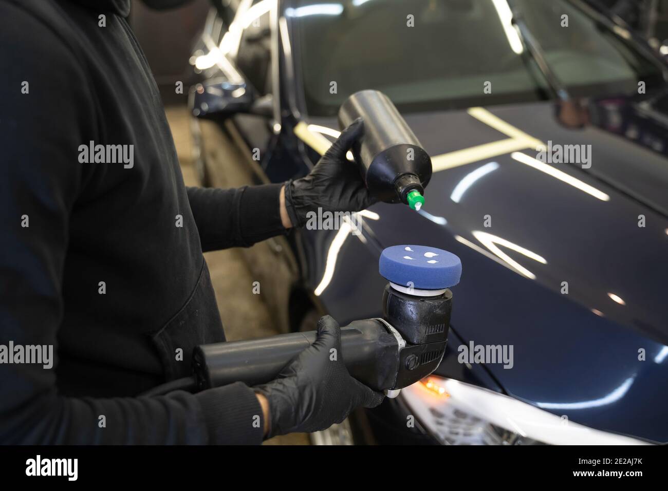 Detailing master applies car polish paste to the polisher. Vehicle