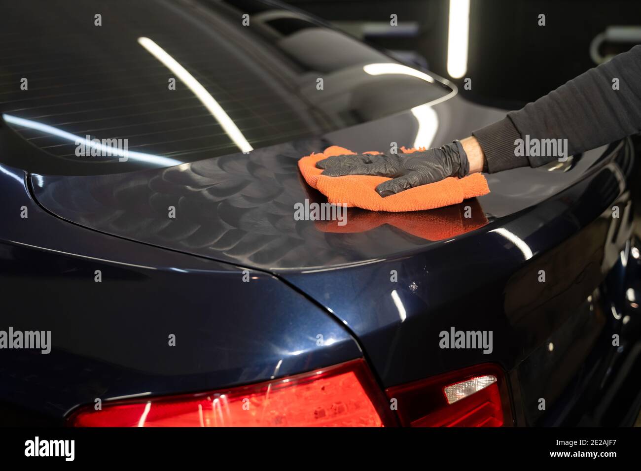 Car polishing process.  Detailing master applies wax for polishing on the vehicle body Stock Photo