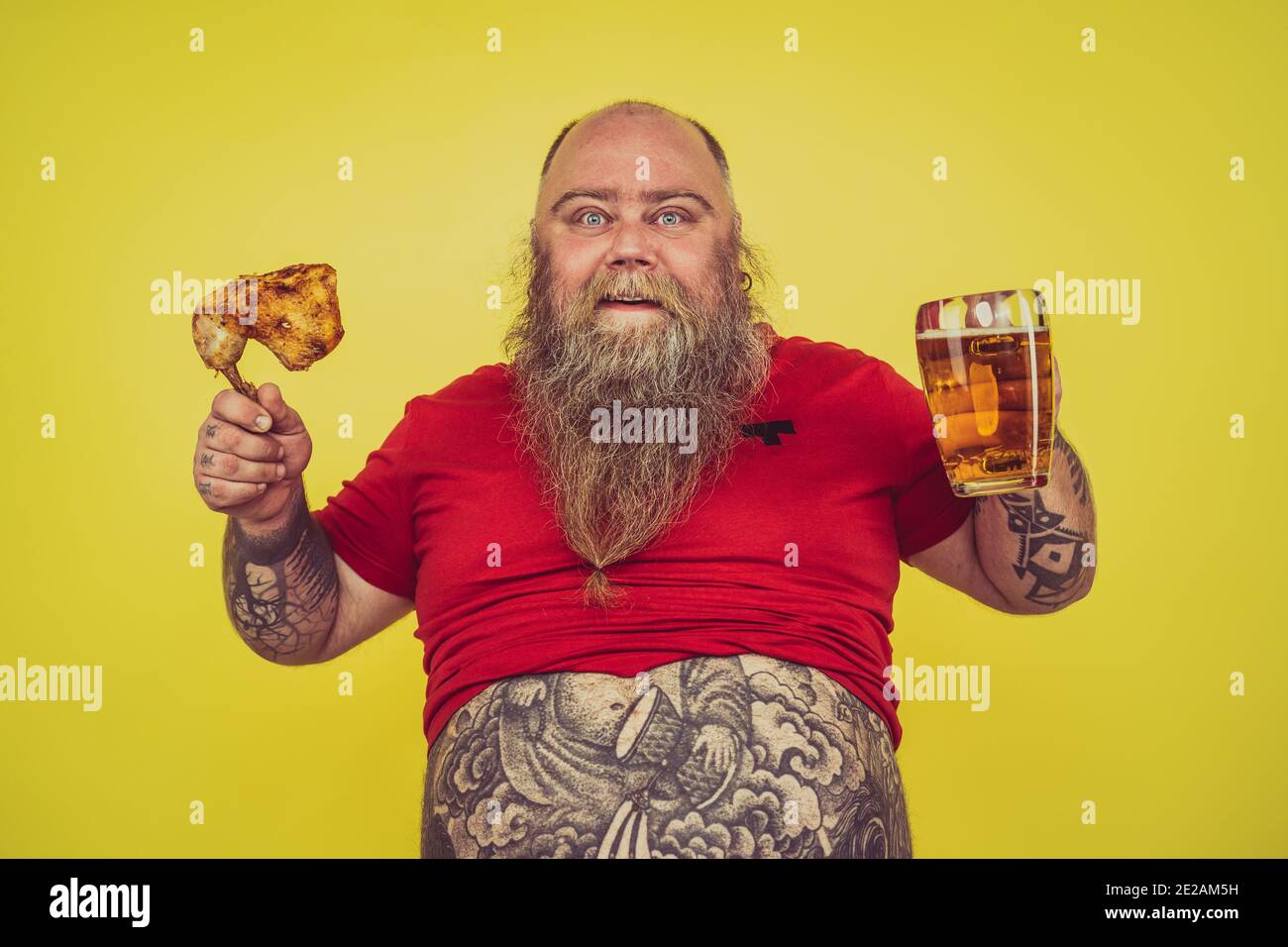 Man watching television while drinking and eating. Funny hipster man portrait on a colored background Stock Photo