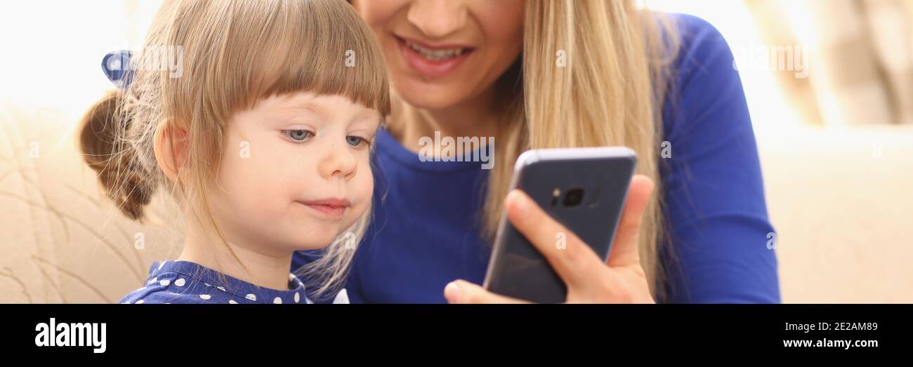 Cute little girl with smiling mom using smartphone Stock Photo - Alamy