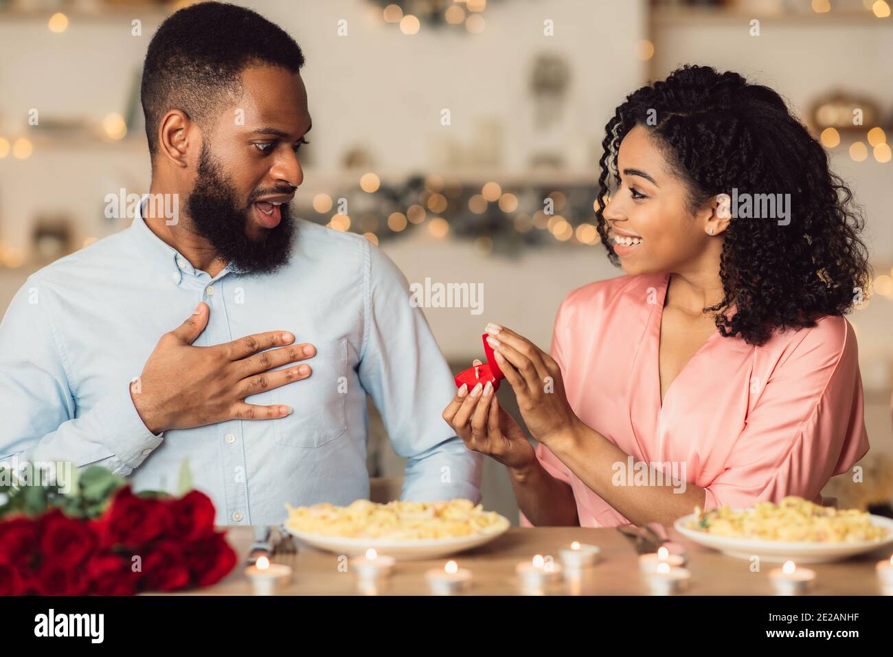 Black woman making proposal with ring to her surprised boyfriend Stock