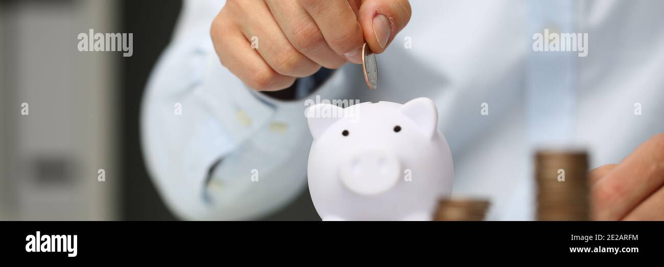 Adult man putting coins into piggy bank Stock Photo - Alamy