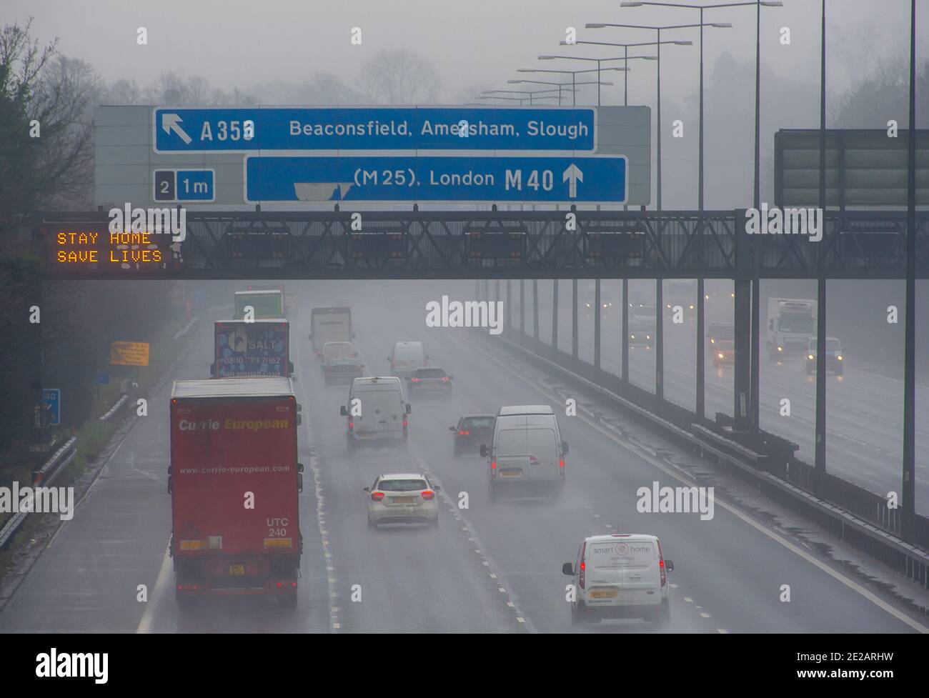Holtspur, Buckinghamshire, UK. 13th January, 2021. Vehicles pass at Stay Home, Save Lives sign on the M40 at Holtspur this morning. Despite the Covid-19 national lockdown, the roads are much busier than during the first Coronavirus lockdown last March. Credit: Maureen McLean/Alamy Live News Stock Photo