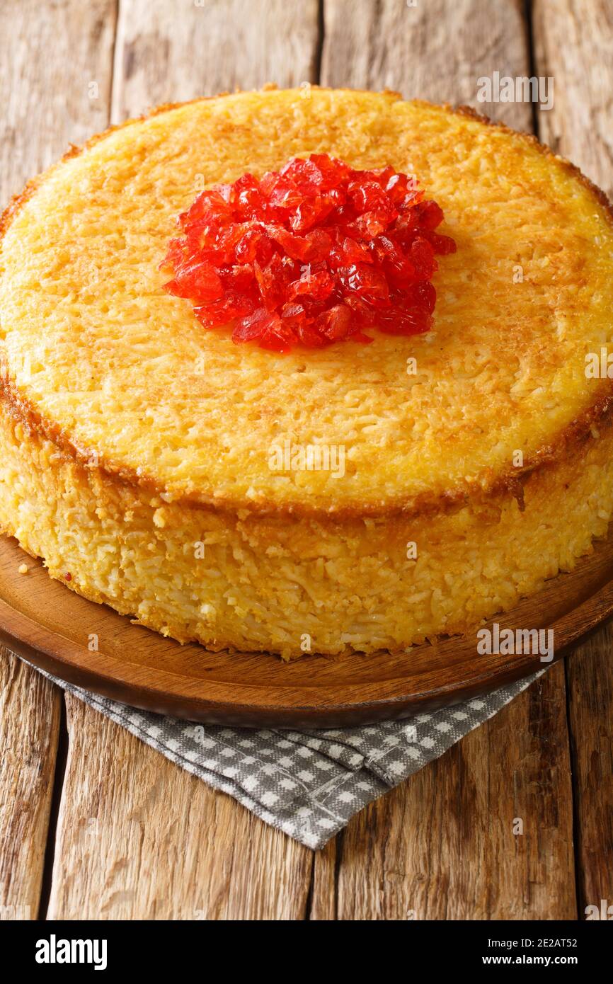 Tasty tahchin, a Persian dish of a baked rice, chicken, and yogurt colored by saffron closeup in the plate on the table. Vertical Stock Photo