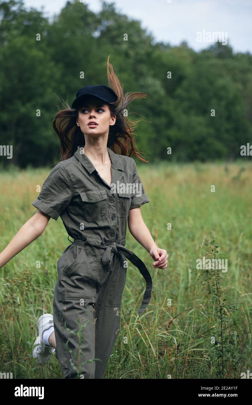 woman outdoors in a green suit black cap jogging across the field  Stock Photo