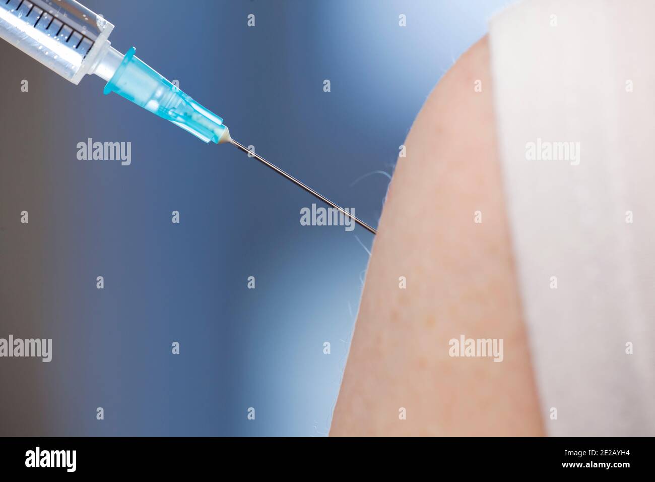 Close-up of vaccination with syringe in upper arm - focus on the needle Stock Photo