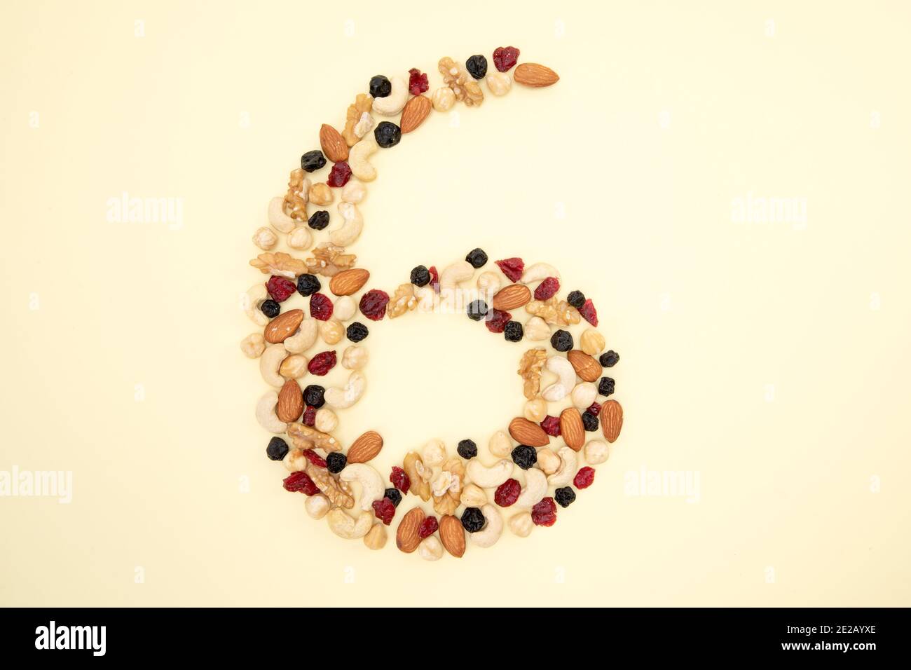 High angle shot of nuts and seeds shaped like number 6 on a yellow ...