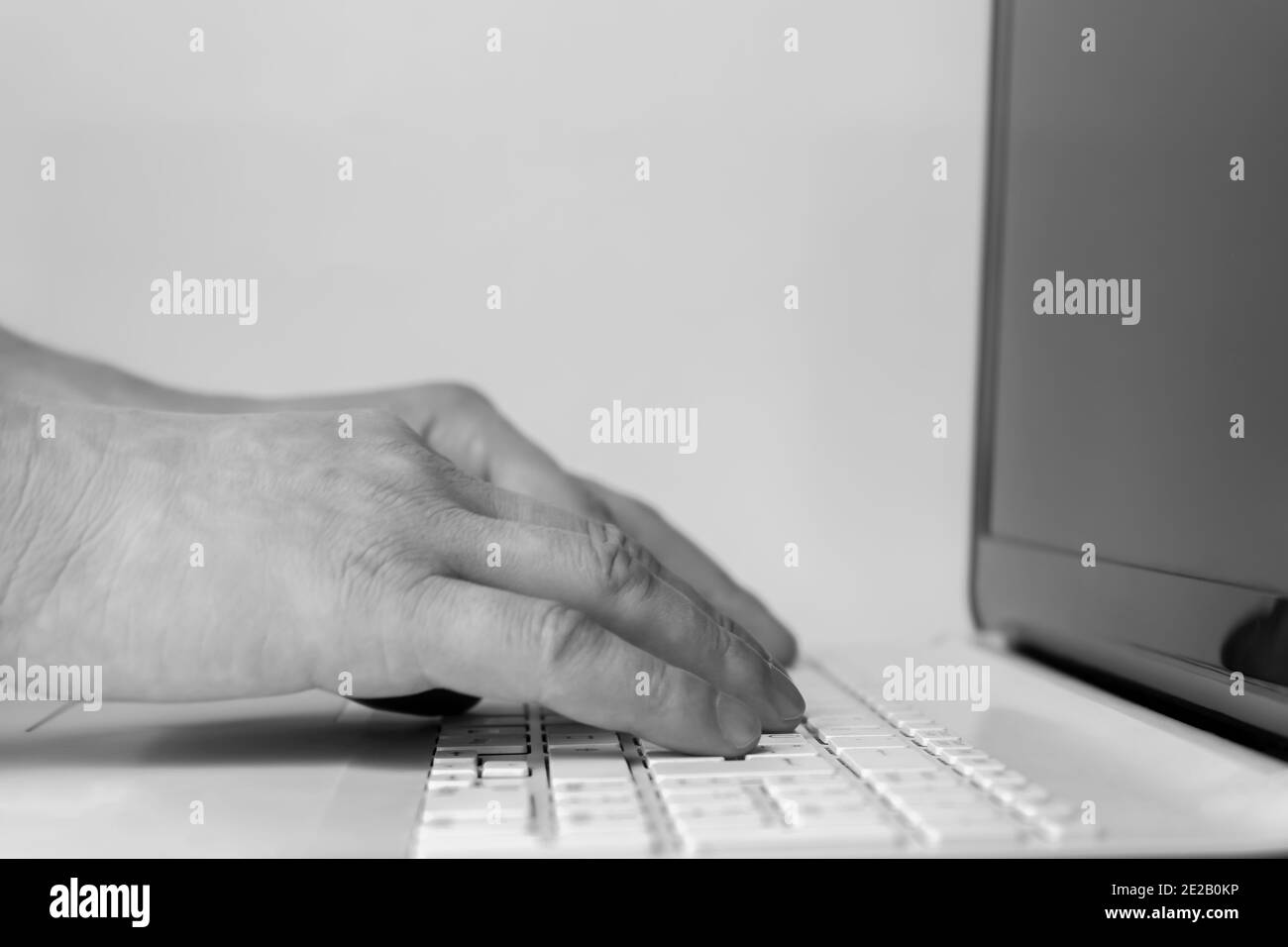 Black and white concept lifestyle of man working typing on computer laptop in office or home. Stock Photo