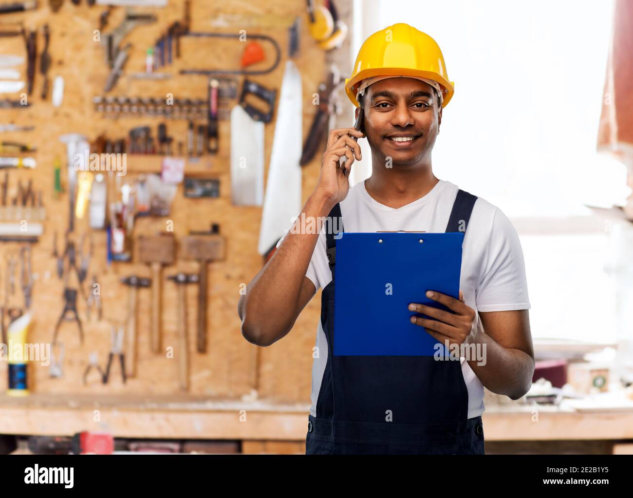 indian builder with clipboard calling on cellphone Stock Photo