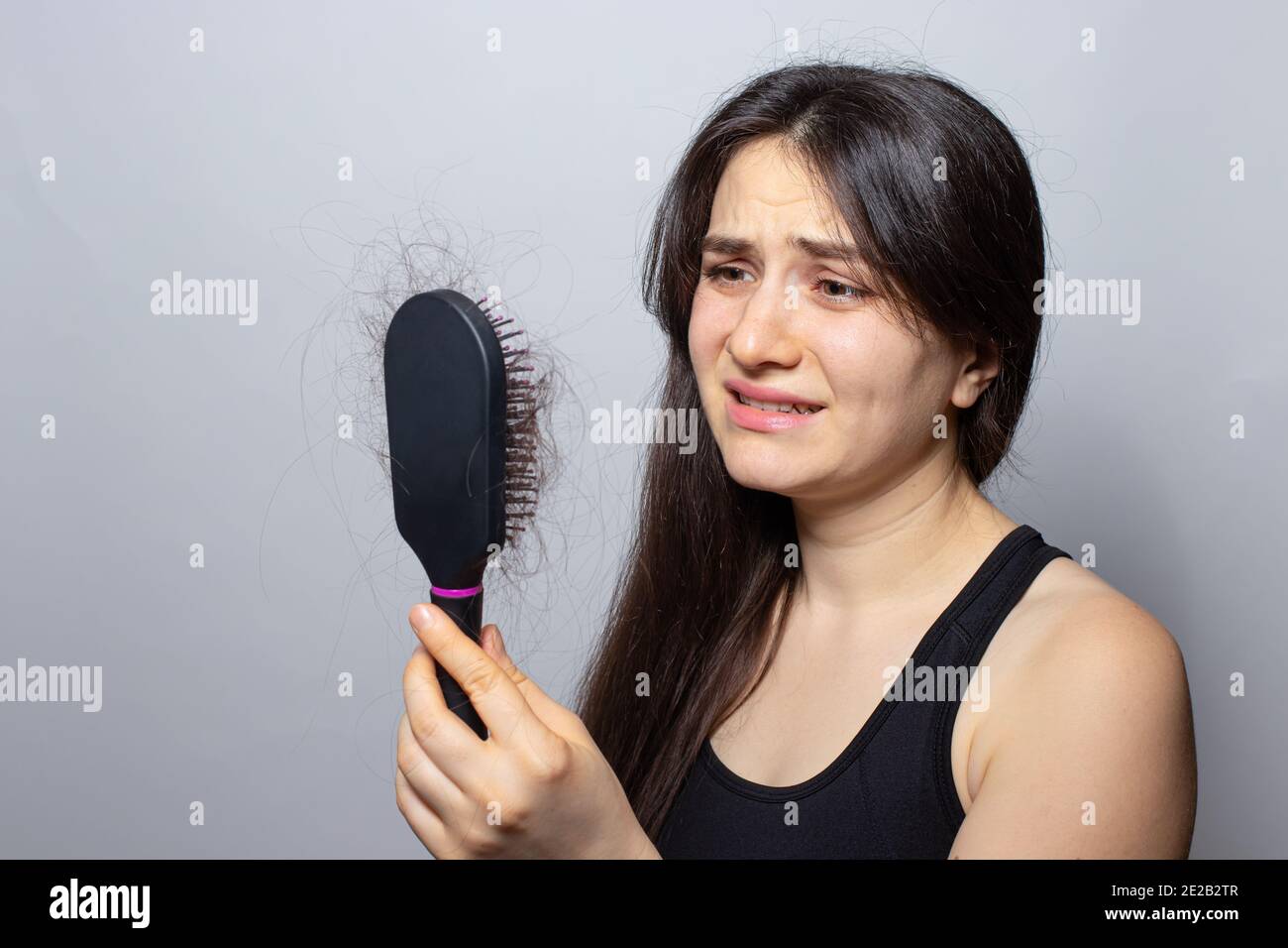 The girl holds a comb for hair with fallen hair. Hair loss, hair care. Stock Photo