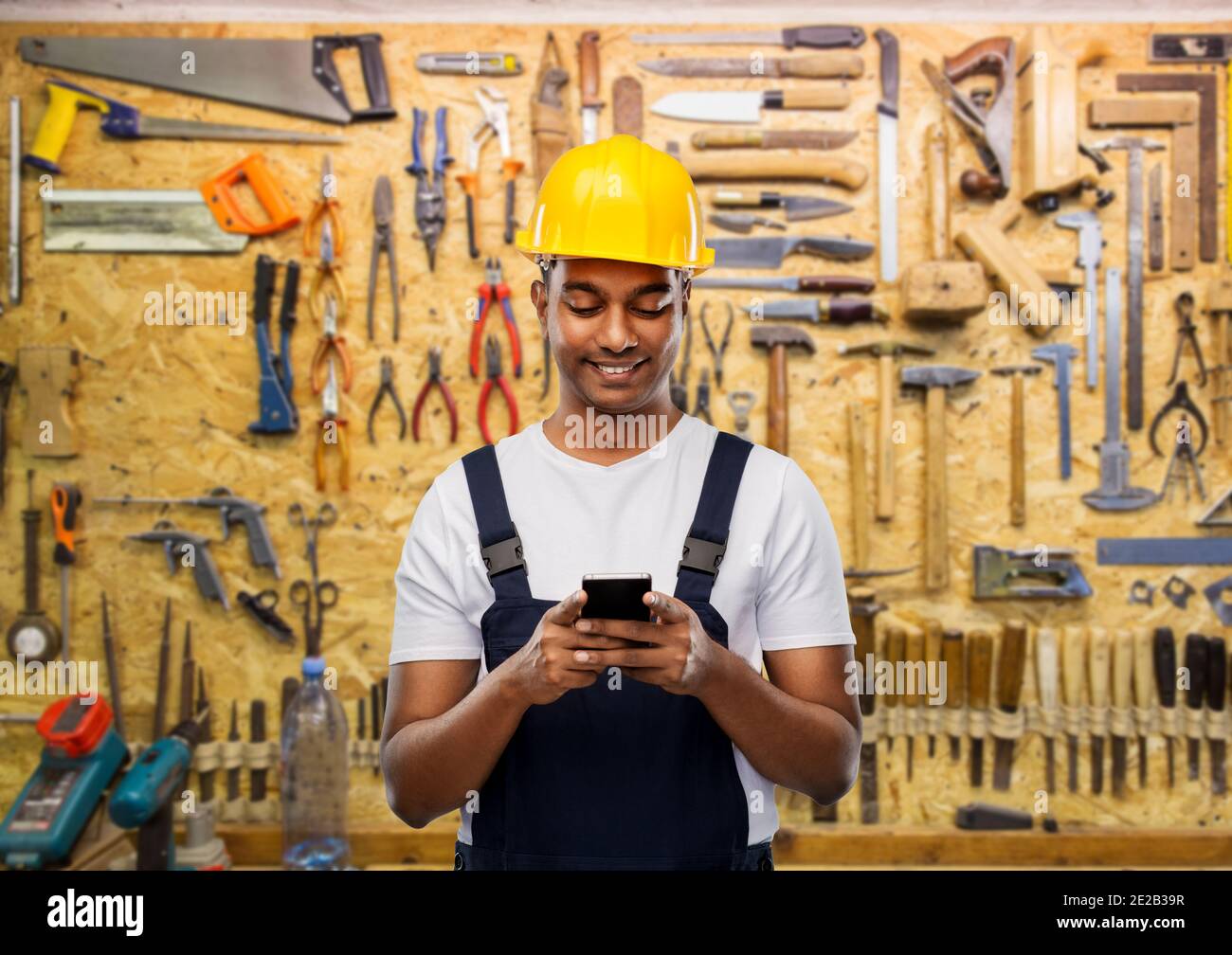 happy indian or builder in helmet using smartphone Stock Photo