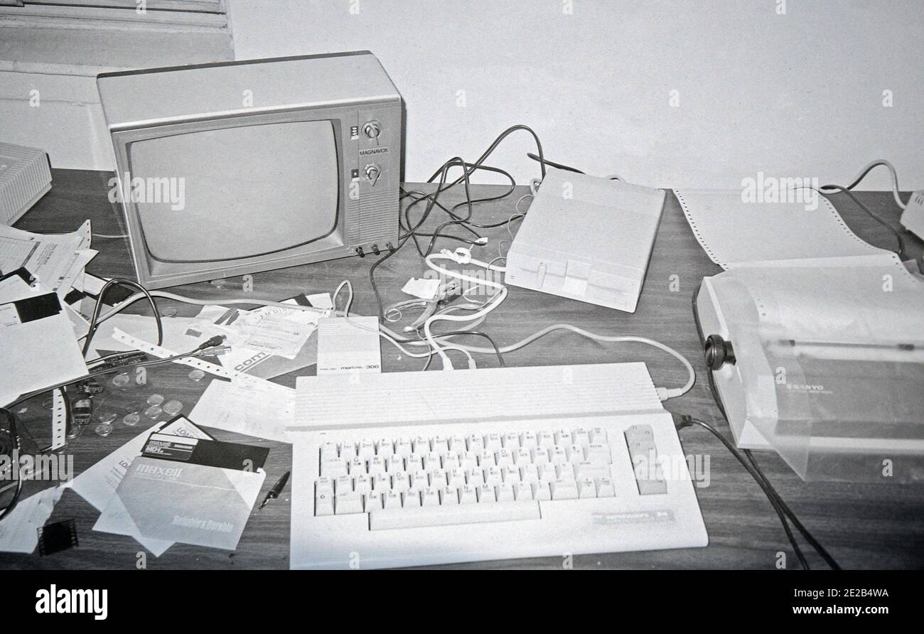 A sloppy home work station in the 1980s, featuring a Commodore 64 Computer hooked up to a black and white TV, 5 1/4 inch floppy drive, a 300 Baud Modem, and a dot-matrix printer Stock Photo