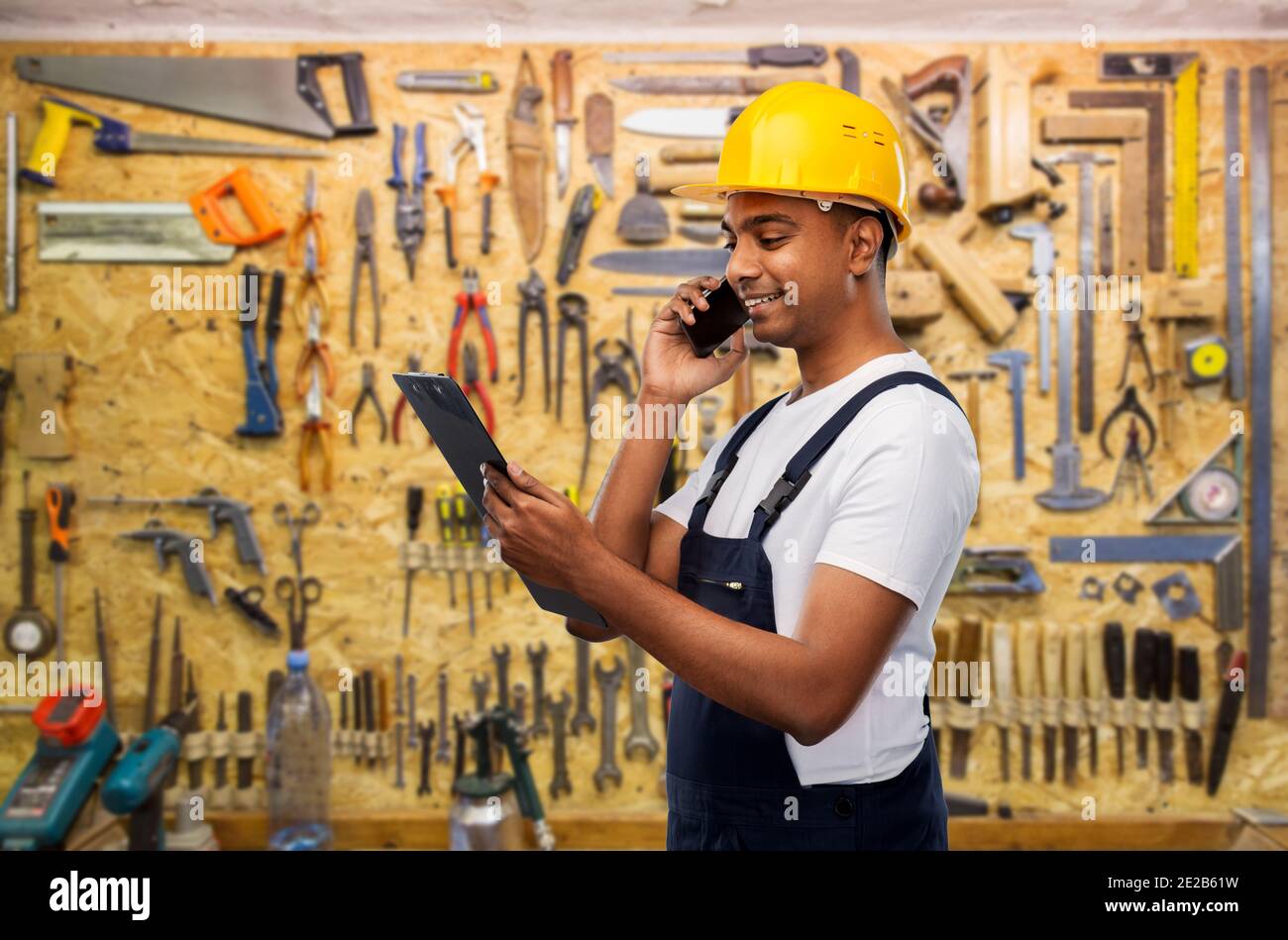 indian builder with clipboard calling on cellphone Stock Photo
