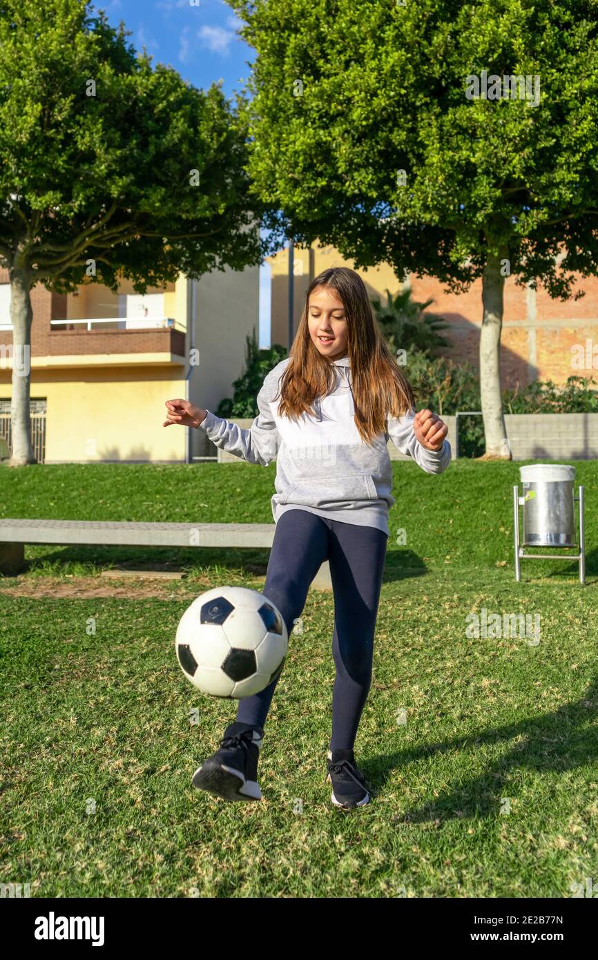 Beautiful little girl playing soccer in a nice park with natural grass ...