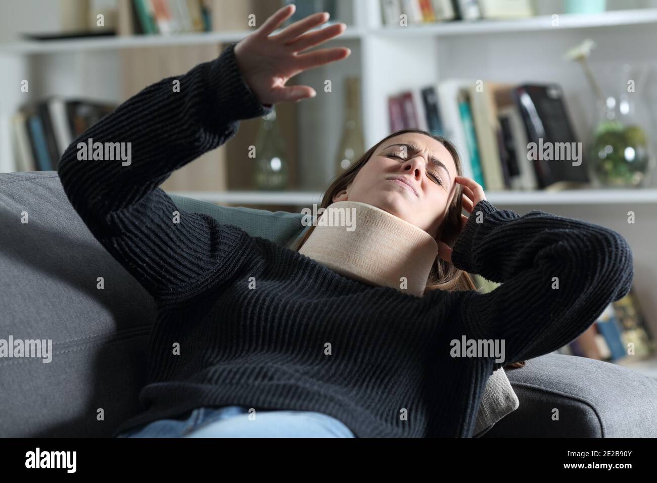 Dizzy disabled woman with neck brace suffering lying on a couch at home Stock Photo