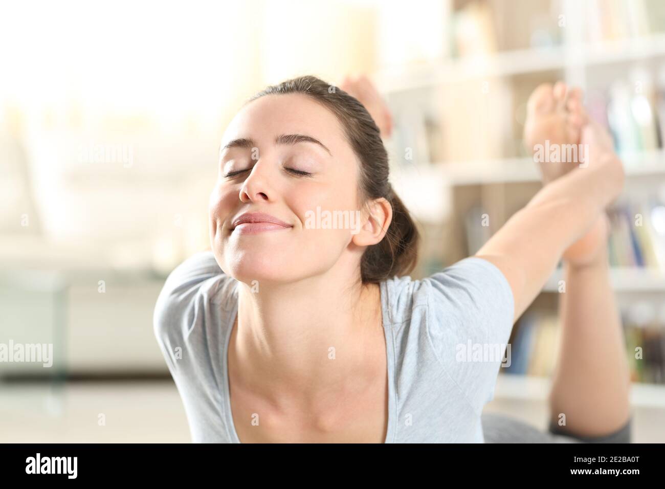 Happy woman doing yoga arc posture exercise on the floor at home Stock Photo