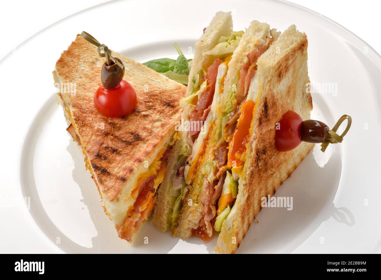 sandwich toast grilled with ham cheese lettuce and tomatoes, cut in half isolated on white Stock Photo