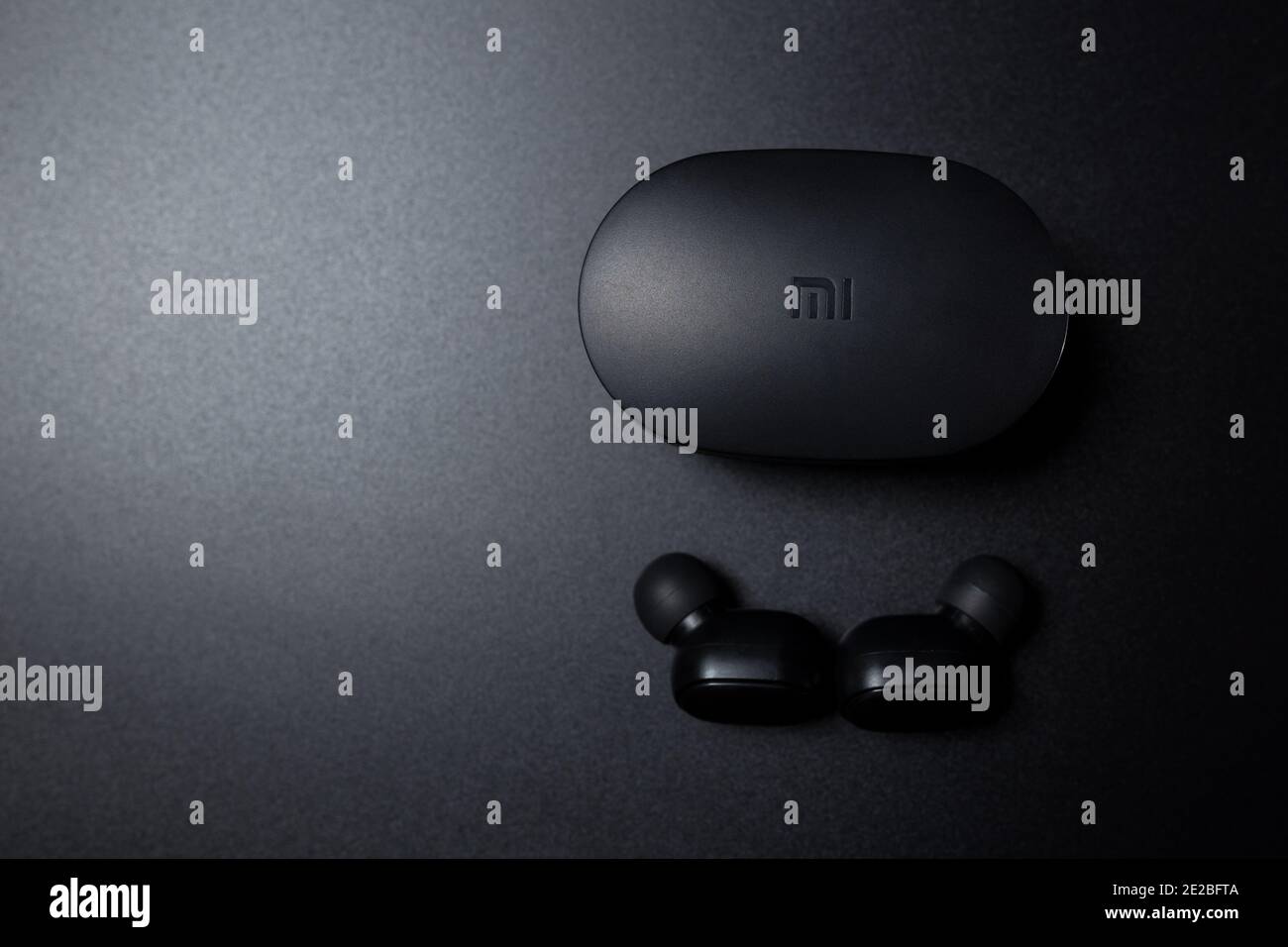 Black bluetooth Xiaomi Airdots on black background with copyspace. Black wireless vacuum earhpones on black. Stock Photo