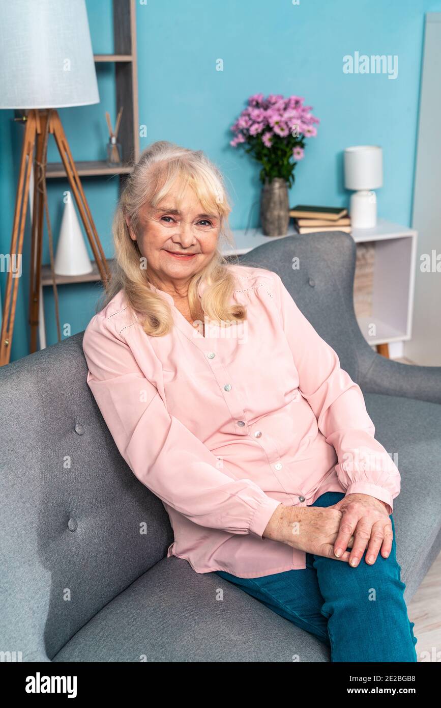 cinematic image of a senior woman sitting on the couch in her beautiful ...