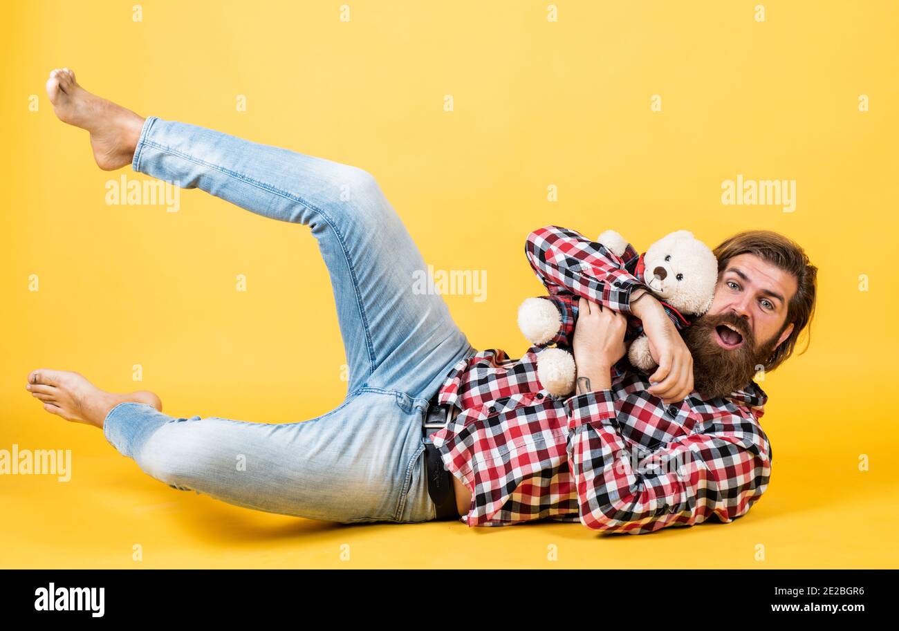 being playful. male feel playful with bear. brutal mature hipster man play with toy. happy birthday. being in good mood. happy valentines day. cheerful bearded man hold teddy bear. Stock Photo