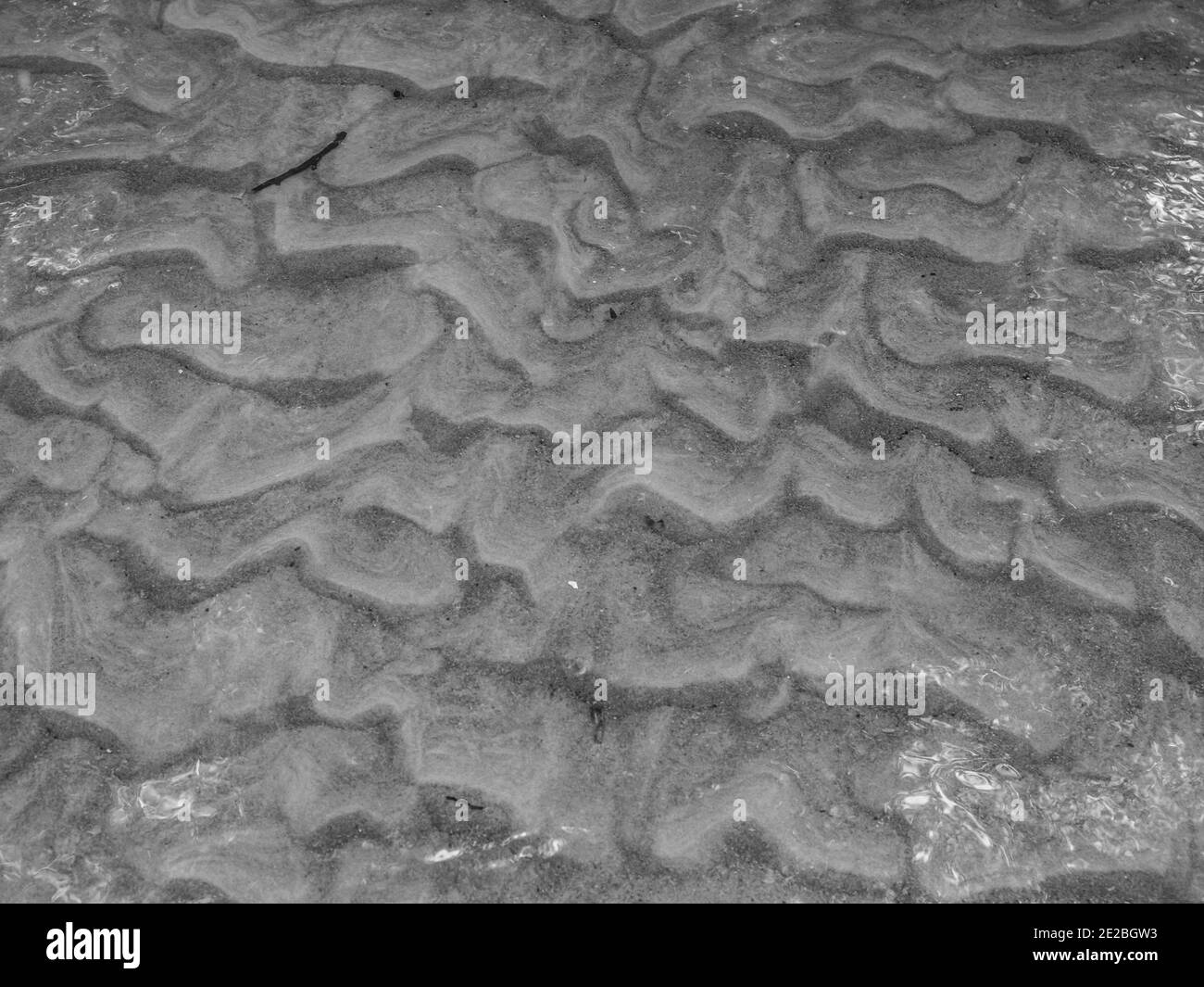 Background, Texture, patterns on the sand under the water in the river in the rays of the setting sun Stock Photo