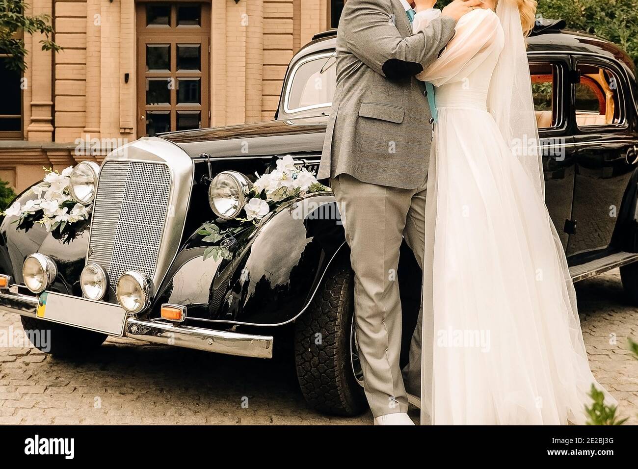 newlyweds hug and dance near the car, the bride and groom hold hands near the retro car Stock Photo