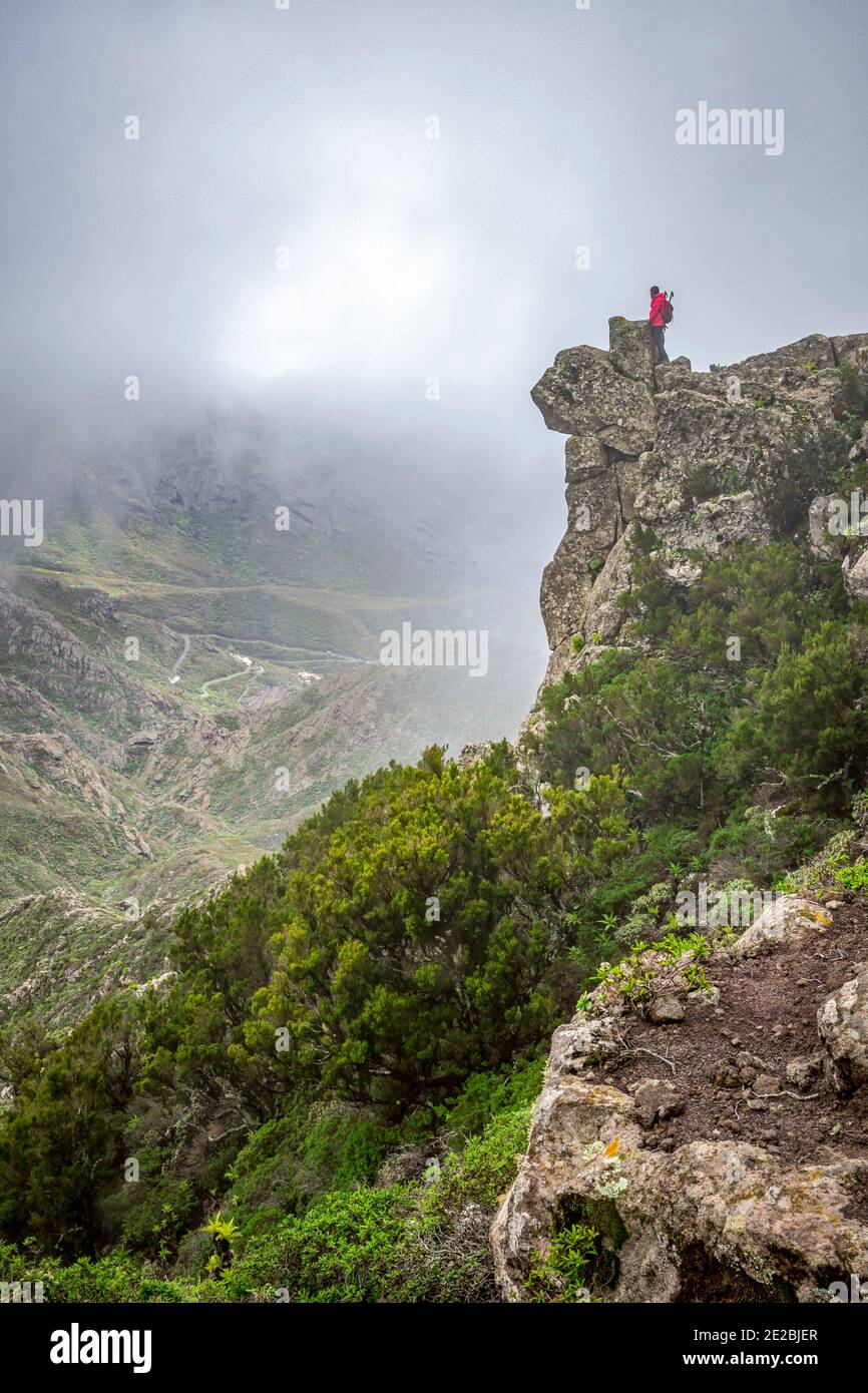 Female tourist looking over valley from cliff in the mist at the Macizo de Anaga national park on the island of Tenerife in the Canary Islands, Spain Stock Photo
