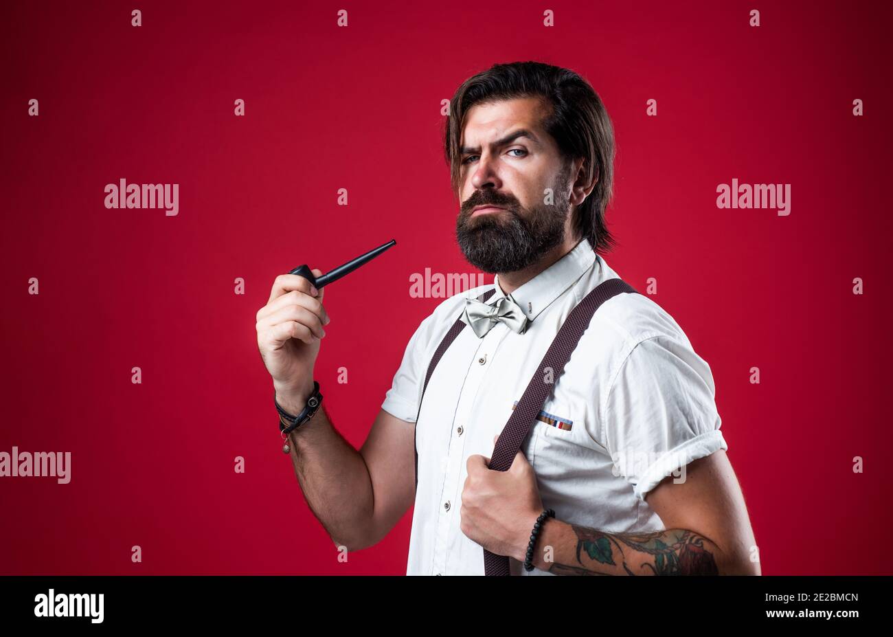 elegant brutal man in formal wear has groomed hair smoking pipe, bad