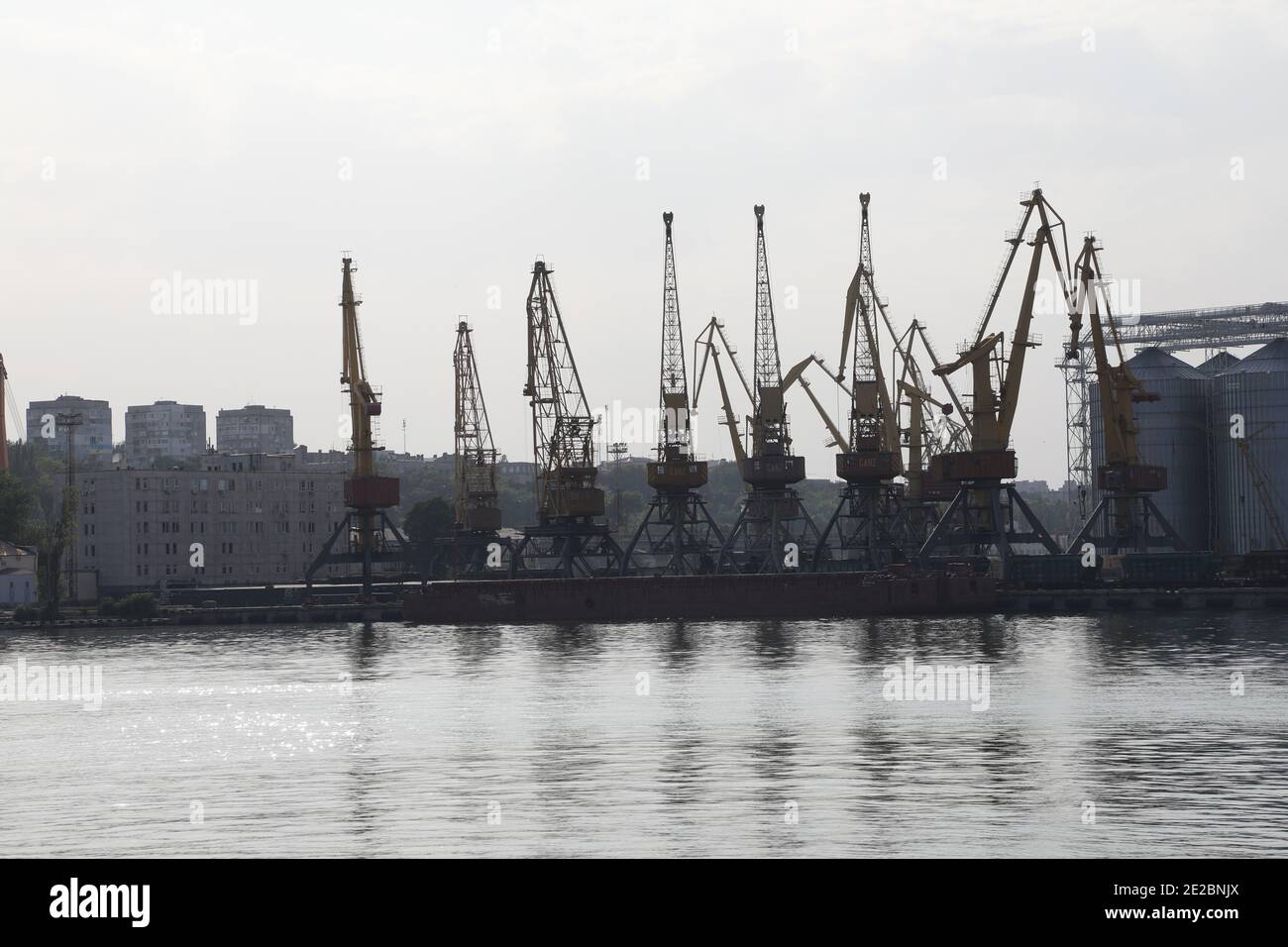 A row of harbor cranes in the port of Odessa, Ukraine, at the Black Sea; reflections in the water. Stock Photo