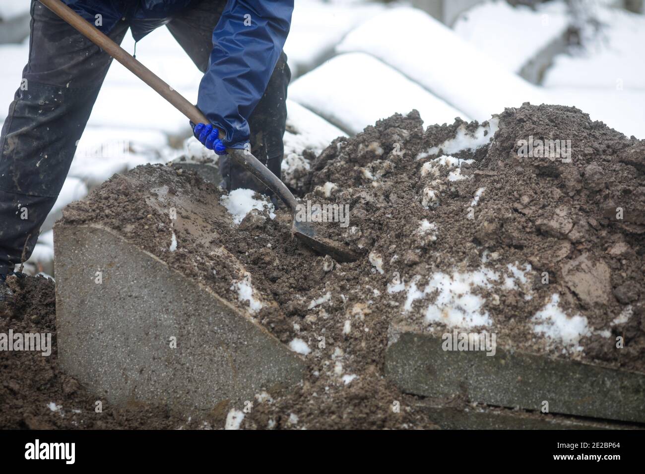Details of a gravedigger covering a tomb with dirt with a shovel during
