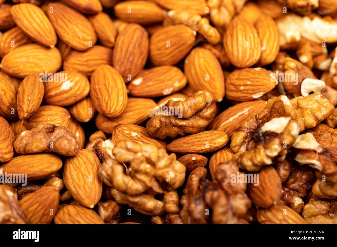 Almonds and walnuts scattered on the table. Close-up, selective focus Stock Photo